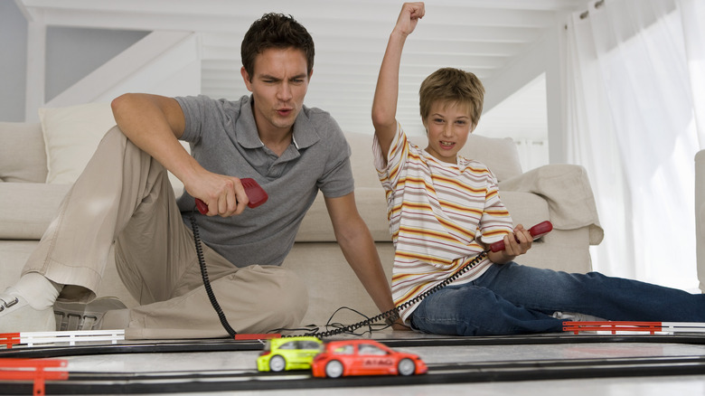 Two boys, one older one younger, playing with slot cars