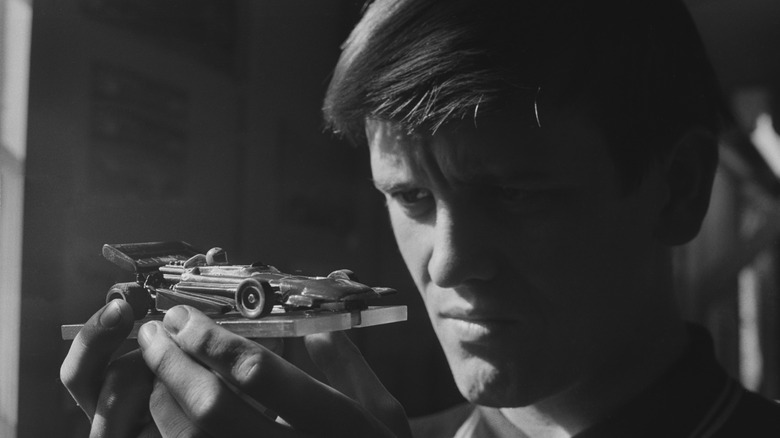 Black and white picture of a man studying a 1970s F1-style slot car