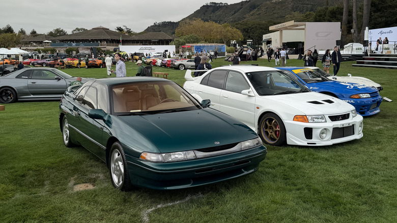 A green Subaru SVX parked on the law at The Quail next to a white Mitsubishi Lancer Evolution V