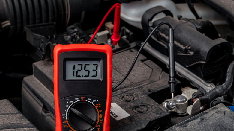 A car battery with a voltmeter attached showing 12.53 volts