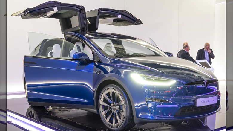 A Tesla Model X with its gull-wing doors open.