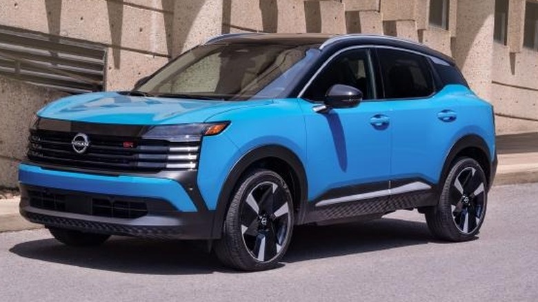 A blue Nissan Kicks drives on a road.