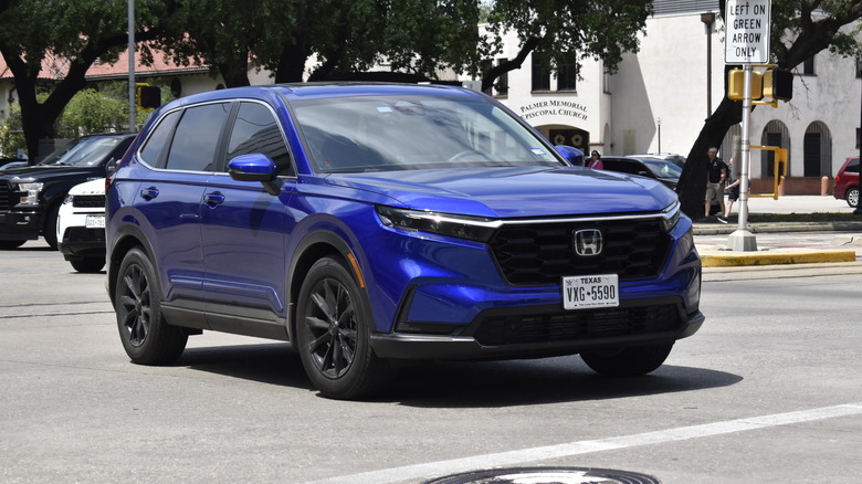 A blue Honda CR-V Hybrid crosses an intersection.