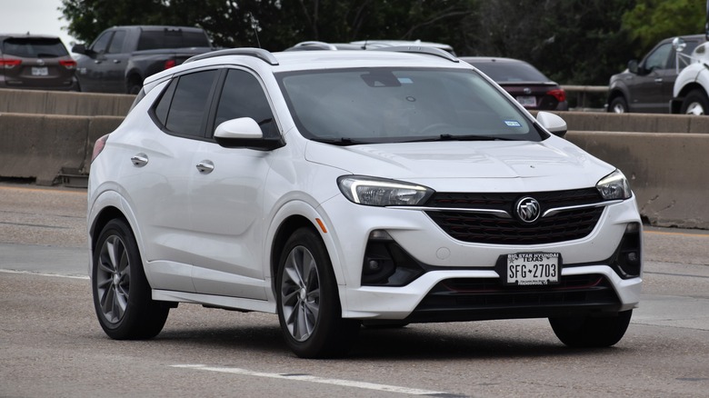 A white Buick Encore GX drives on the highway.