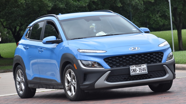 A blue Hyundai Kona sits in a parking lot.