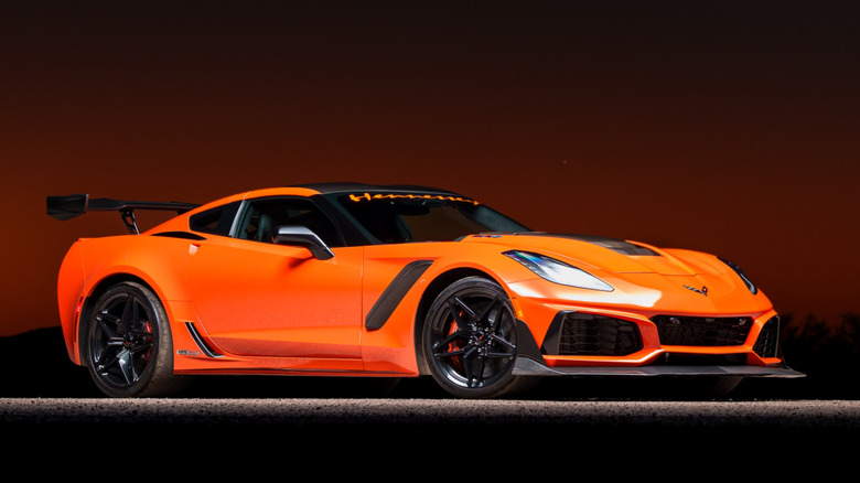 An orange 2019 Chevrolet Corvette ZR1 (ZTK) setup in a showroom with a dark red background.