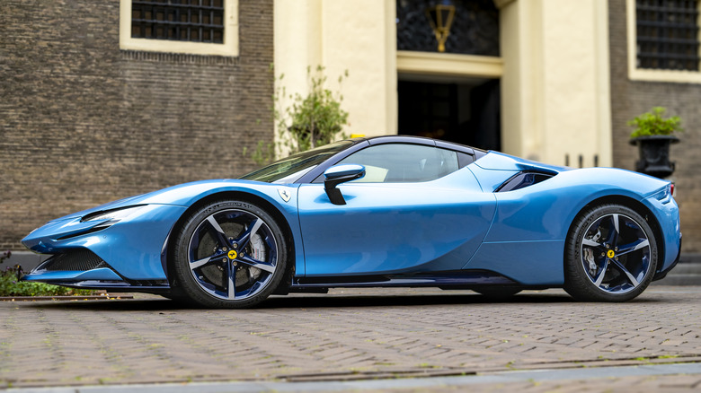 A blue 2021 Ferrari SF90 Stradale Assetto Fiorano parked outside on a brick laid drive.