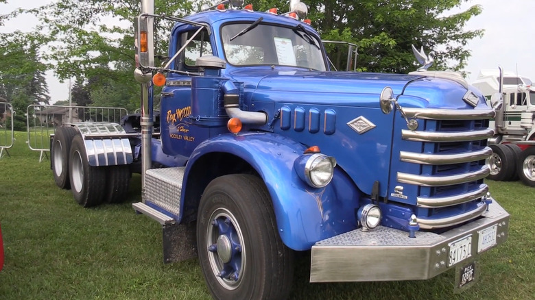 A luxurious metallic blue Diamond T 921 conventional tractor parked on a grass field.