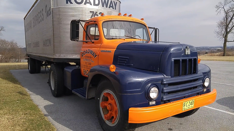A mid-century International Harvester R-190 conventional freight truck parked on an incline, hitched to a vintage Roadway silver trailer.