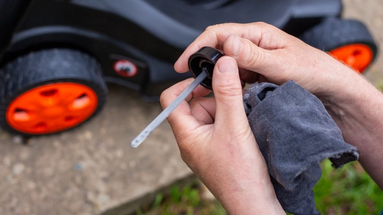 Checking the oil in a lawnmower by looking at the dipstick