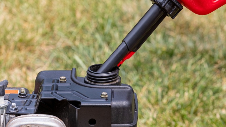Pouring gas into a lawnmower fuel tank