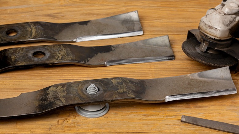 Lawnmower blades on a table with an angle grinder