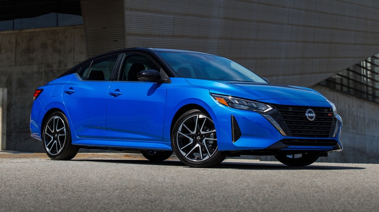 Blue 2025 Nissan Sentra parked on a paved surface in front of a building