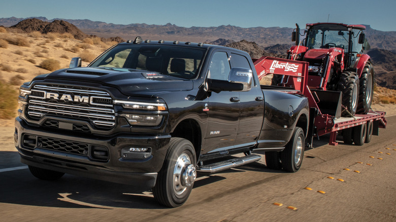 Black 2025 Ram 3500 Laramie dually towing a tractor on a flatbed trailer