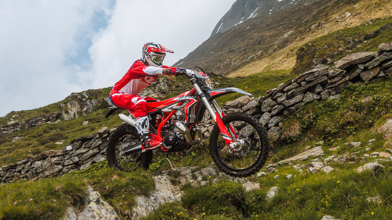 A technical shot of a red and white 2026 Beta Xtrainer 300 "Lowboy" climbing a steep, rocky mountain path.