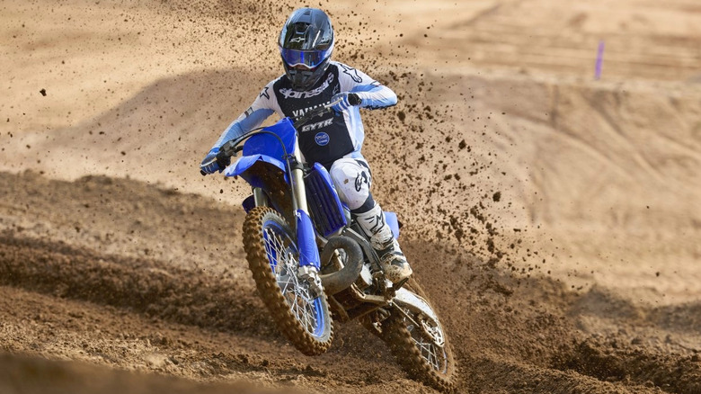 A rider on a 2026 Yamaha YZ250 cornering at speed on a muddy terrain