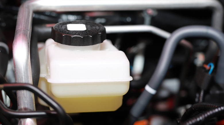 A closer view of the brake fluid reservoir in the engine bay of a car.