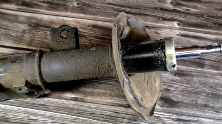 An old and damaged strut with visible oil leaks