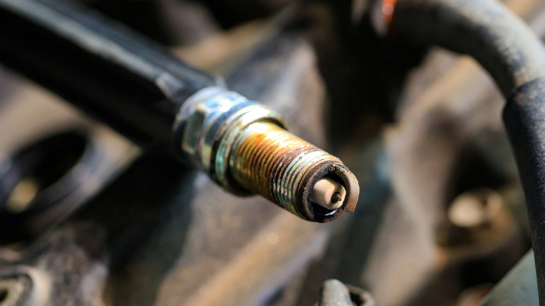 A close up view of an old spark plug with visible dirt and corrosion on the electrodes