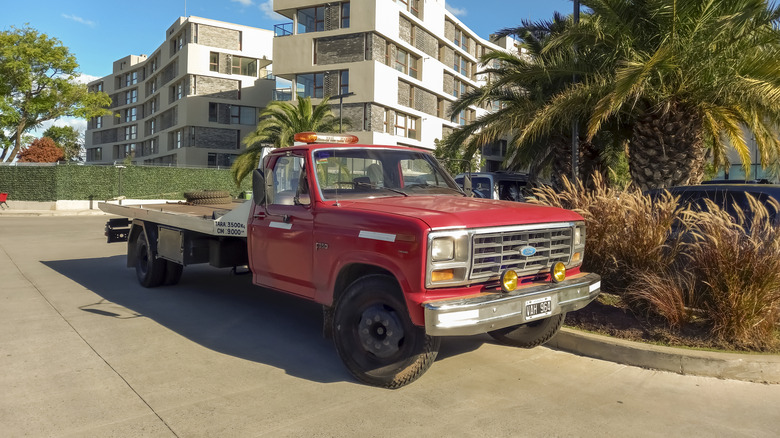 A red flatbed pickup sits parked.