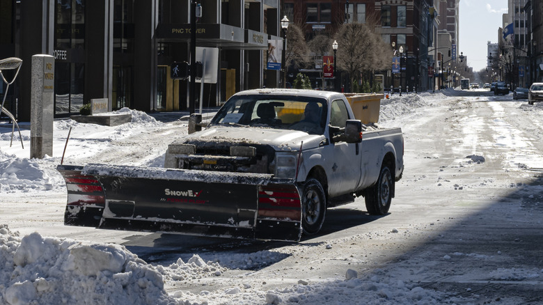 A truck plows snow in a city.