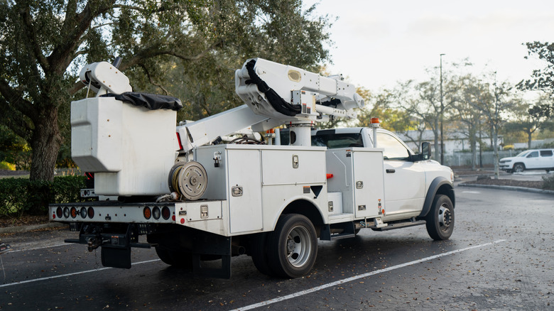 A white utility truck that has compartments sits parked.