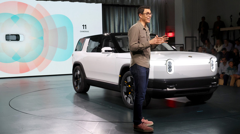 A Rivian R2 displayed at a conference as a man speaks.