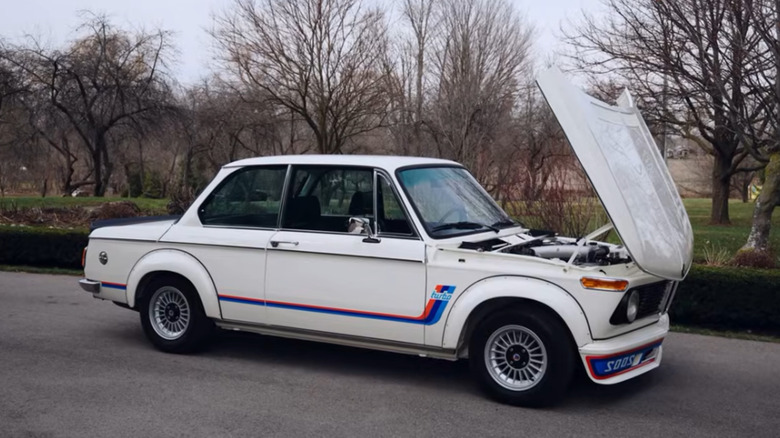 A 1974 BMW 2002 Turbo parked with its clamshell hood opened