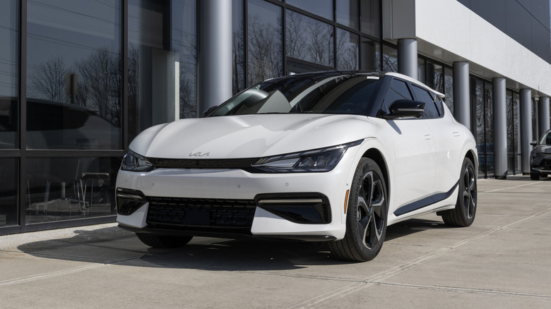 A white Kia EV6 sits outside a dealership.