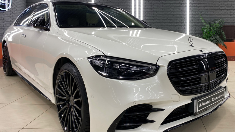 A white Mercedes-Benz S-Class sits in a showroom.