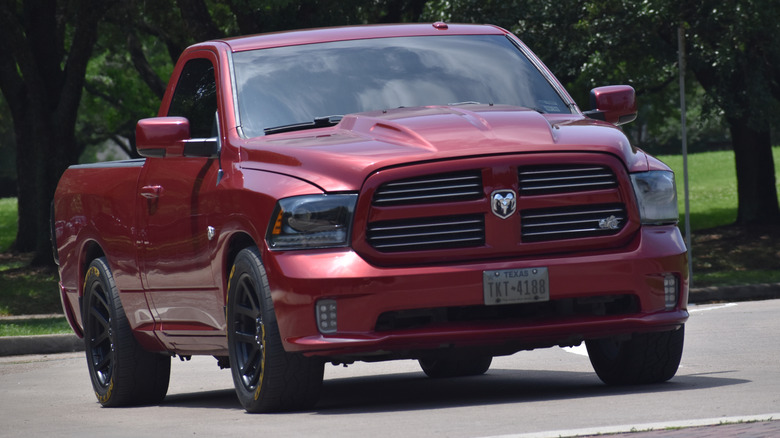 A red Dodge Ram parked outside in parking lot near trees