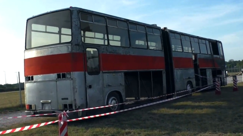 An old Ikarus PALT bus in a state of disrepair by grass