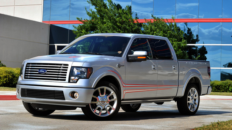 A 2011 Ford F-150 finished here in silver standing in a paved lot in front of a glass-front building.