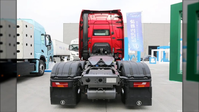 A rear shot of a bright red Shacman X6000 6x4 AMT tractor truck parked outdoors at an exhibition or fleet lot.