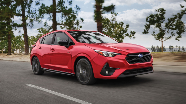 A front 3/4 shot of a 2025 Subaru Impreza on a tree-lined road