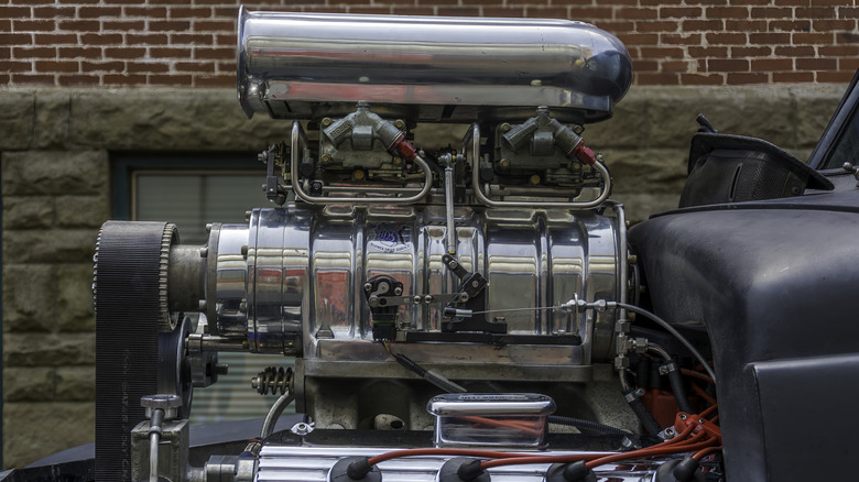 A blown hemi engine sitting in a black hot rod.