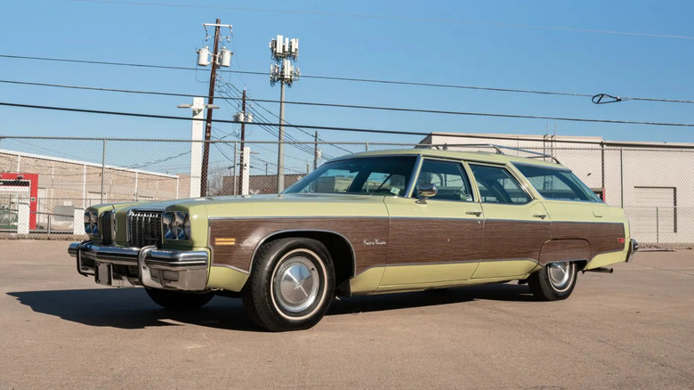 Side view of a green Oldsmobile Custom Cruiser with wood panels parked in front of power lines