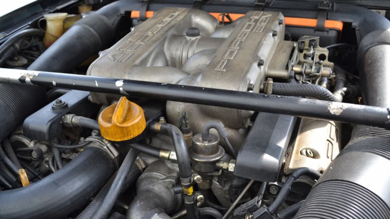 The engine bay of a classic Porsche 928, showing the top of the large front-mounted, water-cooled V8 engine
