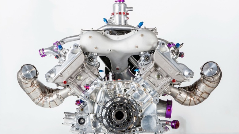 A standalone studio shot of the Porsche 919 Hybrid Le Mans prototype's 2.0-liter V4 race engine against a crisp white backdrop, highlighting its ultra-compact 80-degree block layout