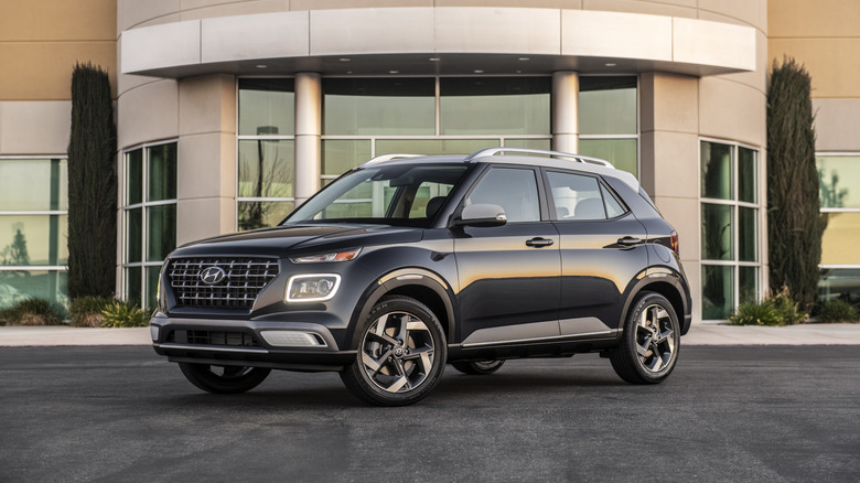 A 2026 Hyundai Venue parked in front of a building with glass windows.