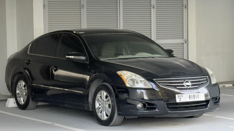 A black Nissan Altima parked in a lot