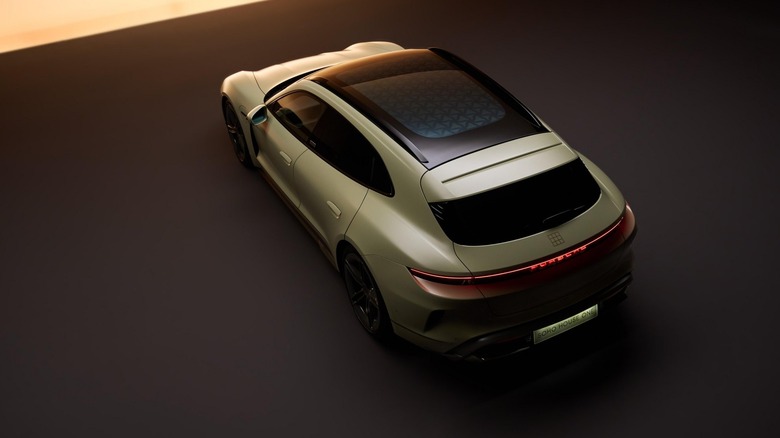 A high-angle studio shot of a pale green Porsche Taycan Turbo S Sport Turismo wagon, showcasing the patterned glass panoramic roof and full-width rear LED lightbar.