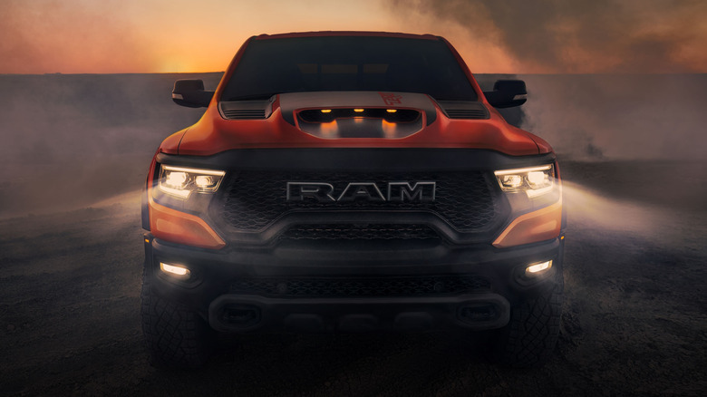 An orange 2021 Ram 1500 TRX shines its headlights through a dusty fog.