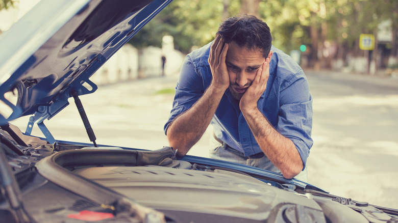 Young stressed man having trouble with his broken car