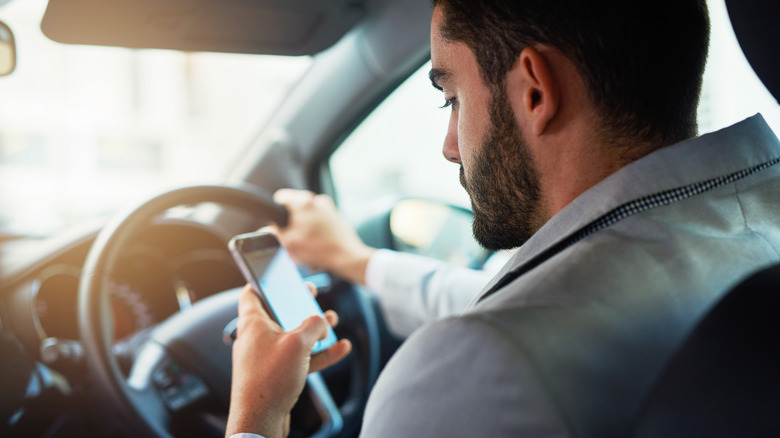 Cropped shot of a man using his phone while driving