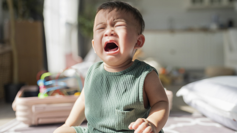 Crying toddler asian baby boy sit on rug carpet he is feel lonely and need parent hold him up for support