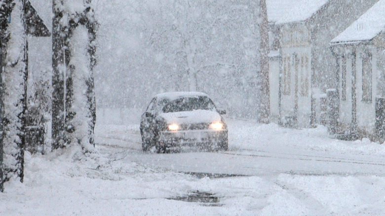 Car driving down snowy thoroughfare successful Germany pinch its lights on