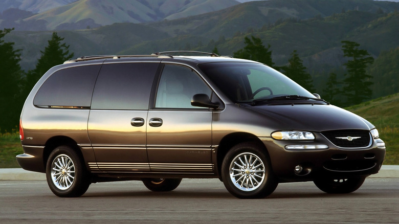 Chrysler Town & Country parked in front of tall trees and mountains