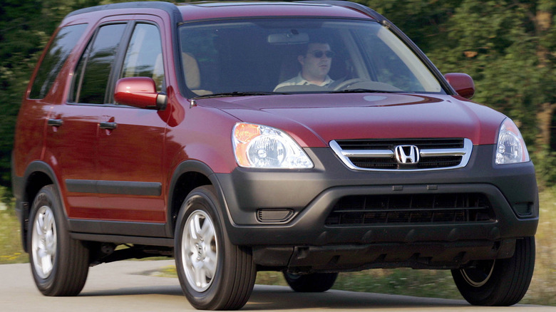Honda CR-V being driven on a winding road with trees behind it
