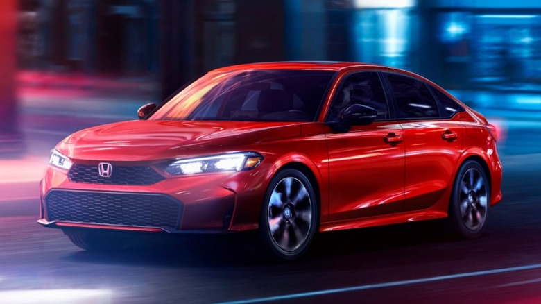 A red 2026 Honda Civic sedan driving on a city street at night